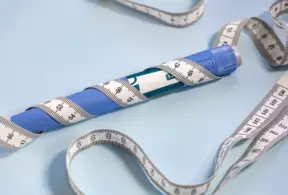 Blue weight-loss pen with a measuring tape around it, a popular tool to aid in weight loss and body measurement control.