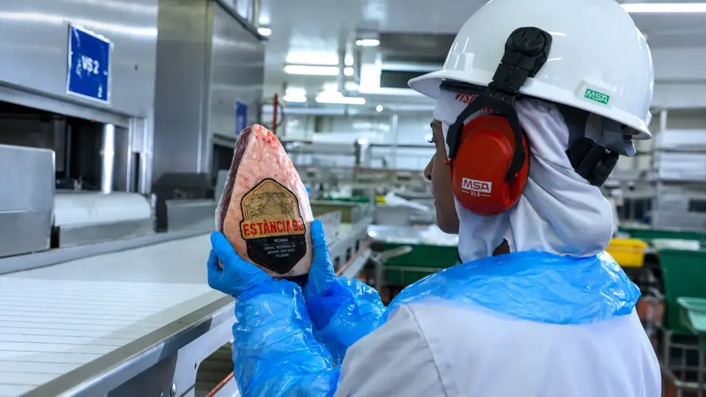 SIF: Workers wearing PPE in an industrial environment; one professional is wearing a hard hat and ear protection, while another holds a part for inspection bearing an "Estância 3D" label, in a production area.