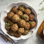 Un tazón con albóndigas de carne magra (patinho) y una salsa al lado. Ilustra el concepto de precauciones en el consumo de carne bovina.