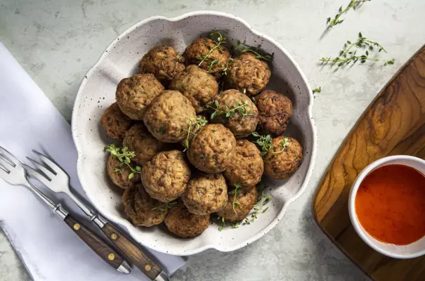 Un tazón con albóndigas de carne magra (patinho) y una salsa al lado. Ilustra el concepto de precauciones en el consumo de carne bovina.