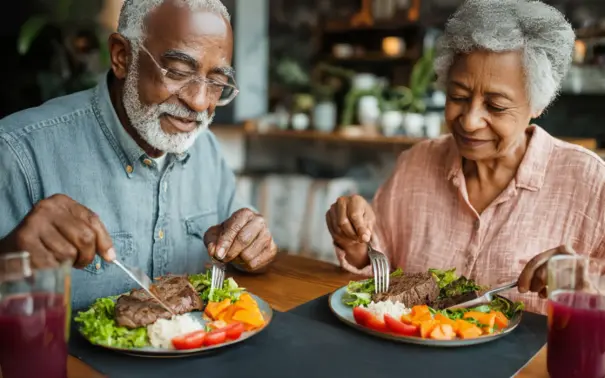 Personas mayores disfrutando de una comida saludable, rica en proteínas, ideal para el mantenimiento de la masa muscular en la tercera edad.