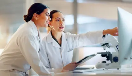 Dos científicas analizando resultados de investigación sobre prebióticos y probióticos en un laboratorio de microbiología veterinaria, con enfoque en la nutrición animal.