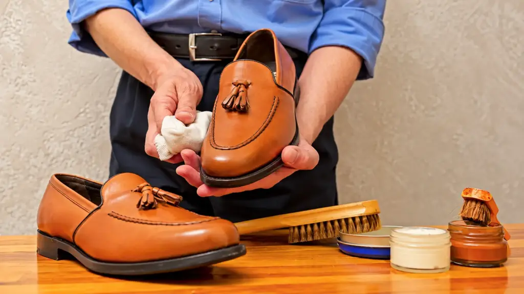 Día Nacional de la Ganadería: un zapatero aplica crema a un par de zapatos de cuero marrón sobre un banco de trabajo, con un cepillo y betunes al lado.
