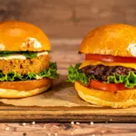 Um hambúrguer de proteína de origem vegetal feito de soja e ao lado um hambúrguer de proteína animal, feito de carne bovina