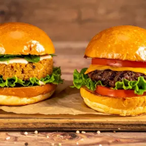 Um hambúrguer de proteína de origem vegetal feito de soja e ao lado um hambúrguer de proteína animal, feito de carne bovina