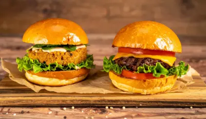 Um hambúrguer de proteína de origem vegetal feito de soja e ao lado um hambúrguer de proteína animal, feito de carne bovina