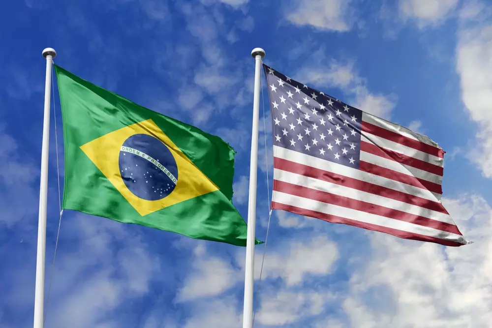 Bandeiras do Brasil e dos Estados Unidos contra um céu azul, simbolizando a superação de tensões entre os governos e impulsionando as exportações.