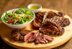 proteína bovina grelhada, acompanhado de uma salada verde fresca e molho