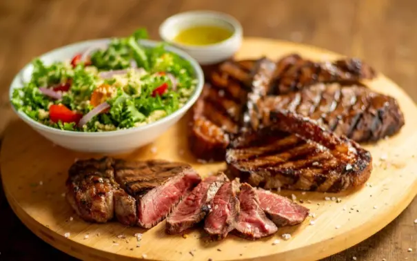 proteína bovina grelhada, acompanhado de uma salada verde fresca e molho