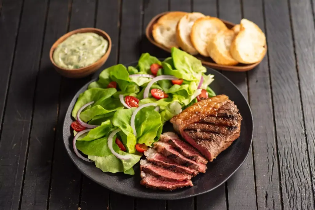 Plate with grilled beef, salad with lettuce, tomato and onion, accompanied by bread