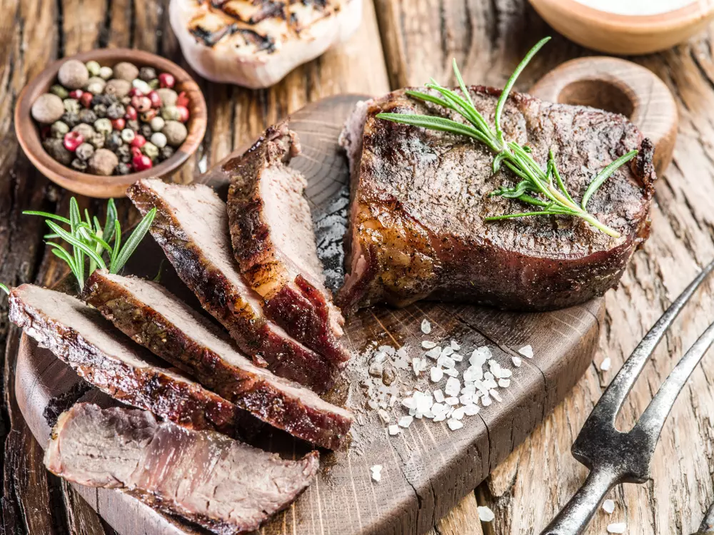 Carne bem passada cortada e pronta para ser servida, com molho e temperos ao lado