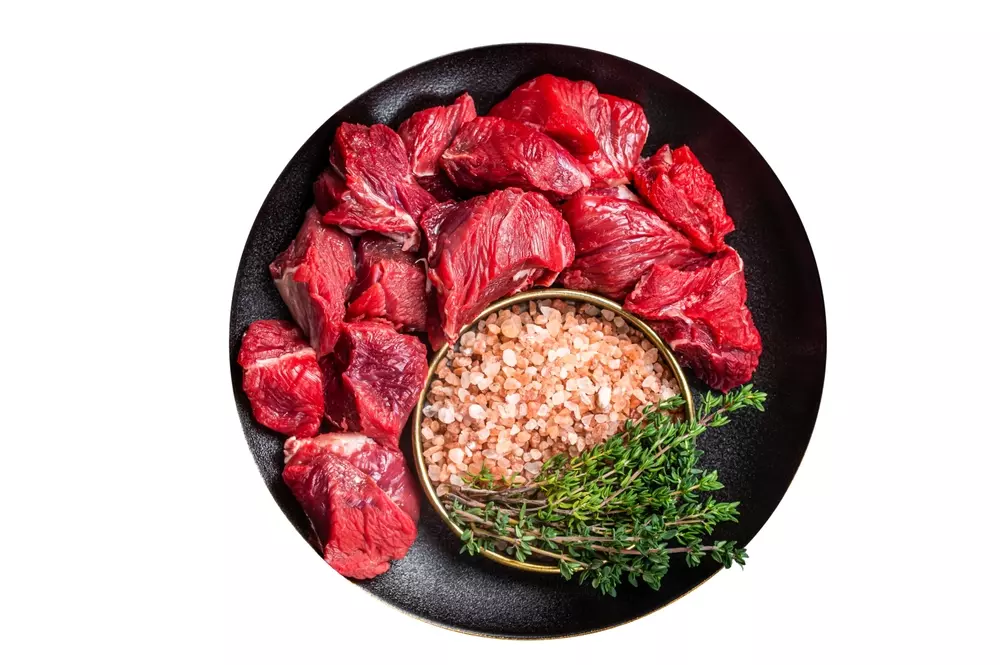Carnes bovinas frescas em cortes, incluindo carne magra, acompanhadas de sal de rock e ervas aromáticas, promovendo a saúde óssea e prevenindo osteoporose.