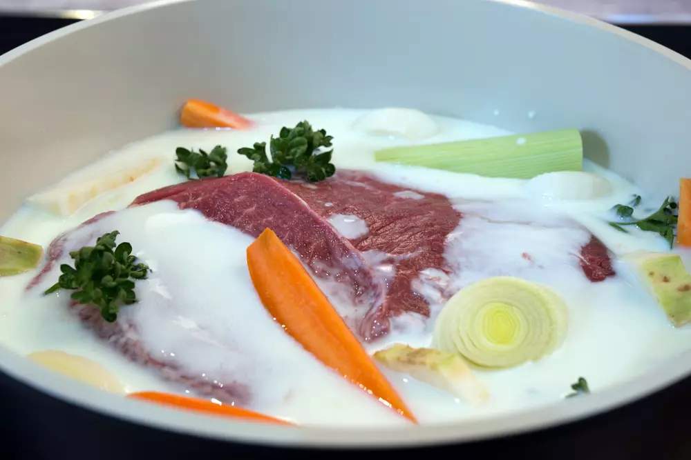 Meat prepared with yogurt and buttermilk accompanied by vegetables, including carrots, onion and seasonings, ideal for recipes using yogurt and buttermilk.