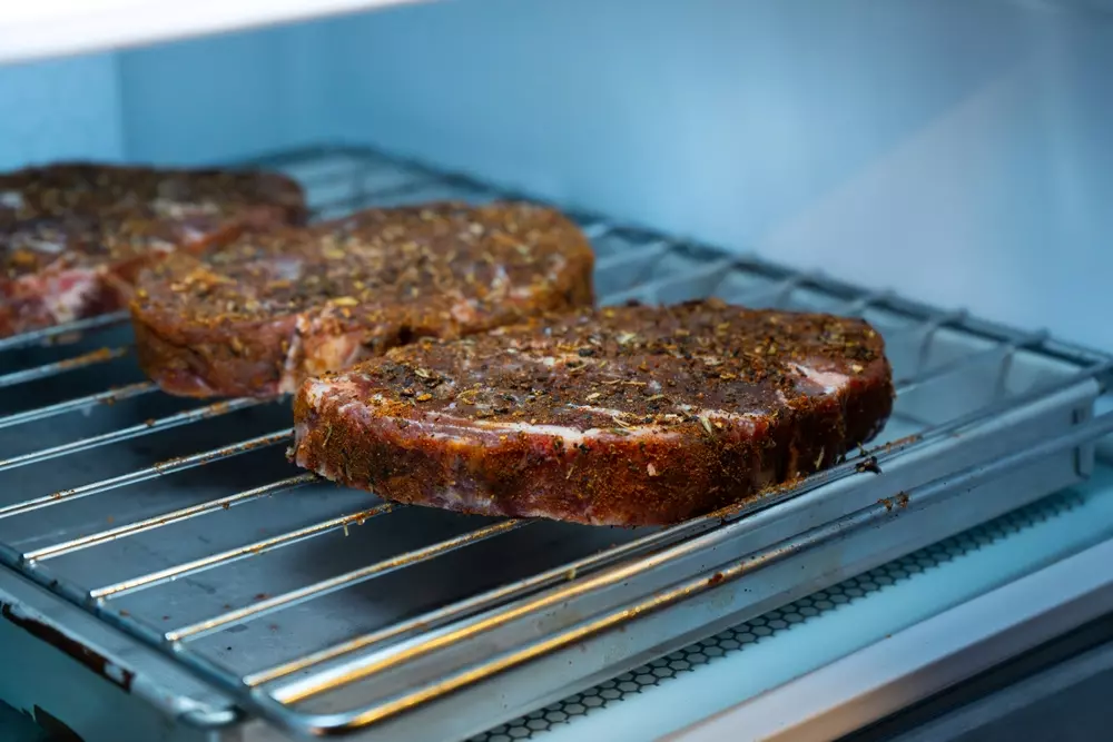 Cuts of meat with dry brine (dry salting) being prepared on the grill, ideal for those seeking preservation techniques and enhanced flavor in meat.