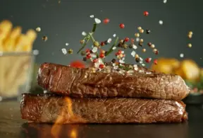 Carne suculenta sendo temperada com pimenta e especiarias para marinada deliciosa, ideal para preparar pratos saborosos na cozinha.