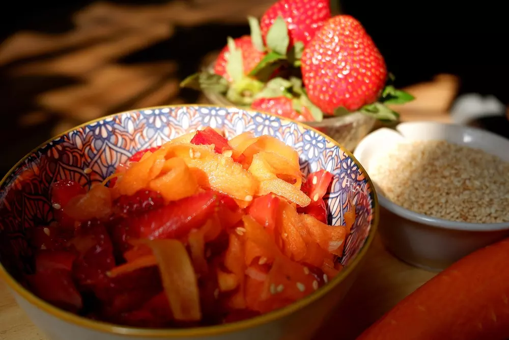 Prepared ingredients to make a fruit-based enzymatic marinade, including a mix of chopped fruits, fresh strawberries and seeds, ideal for cooking in a healthy and natural way.