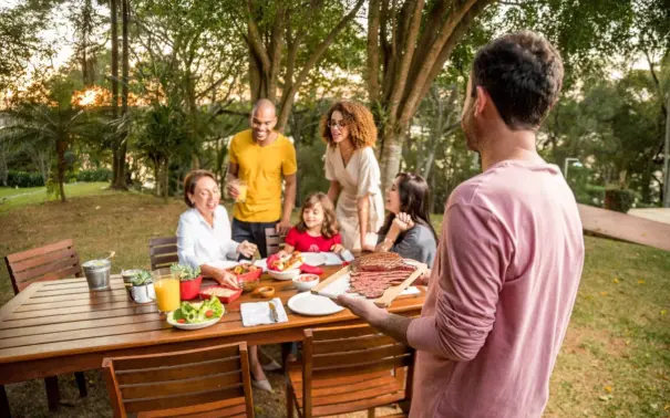Família aproveitando churrasco de chef ao ar livre com menu variado e ambiente descontraído na natureza.
