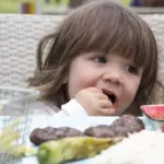 Criança desfrutando de carne bovina em refeição que promove o desenvolvimento cognitivo infantil