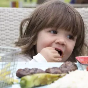 Criança desfrutando de carne bovina em refeição que promove o desenvolvimento cognitivo infantil