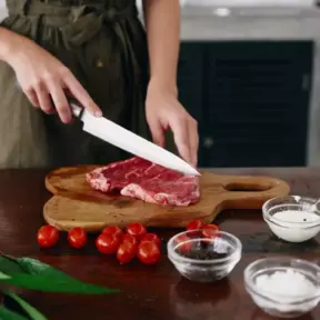 Mulher preparando carne bovina com ingredientes como tomates, sal, pimenta e alho