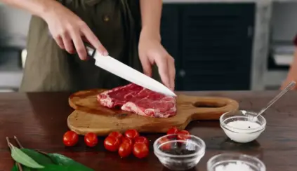 Mulher preparando carne bovina com ingredientes como tomates, sal, pimenta e alho