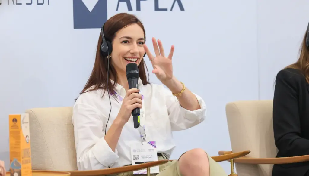 Lívia Padilha, falando ao microfone durante evento, demonstrando liderança feminina no setor de pecuária.