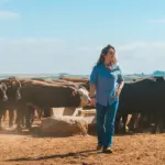 Mulher na pecuária se divertindo ao lado de gado em uma fazenda, evidenciando o papel das mulheres na atividade da pecuária, especialmente na pulqueria.