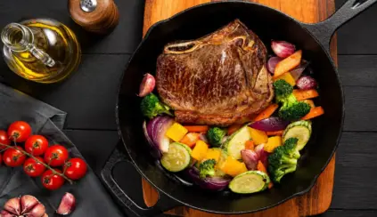 Bife suculento sendo preparado em frigideira com legumes variados. Lembrando que a carne bovina é uma fonte de zinco