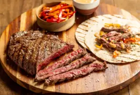 Carne suculenta fatiada ao lado de tortillas e acompanhamentos