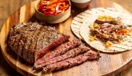 Carne suculenta fatiada ao lado de tortillas e acompanhamentos