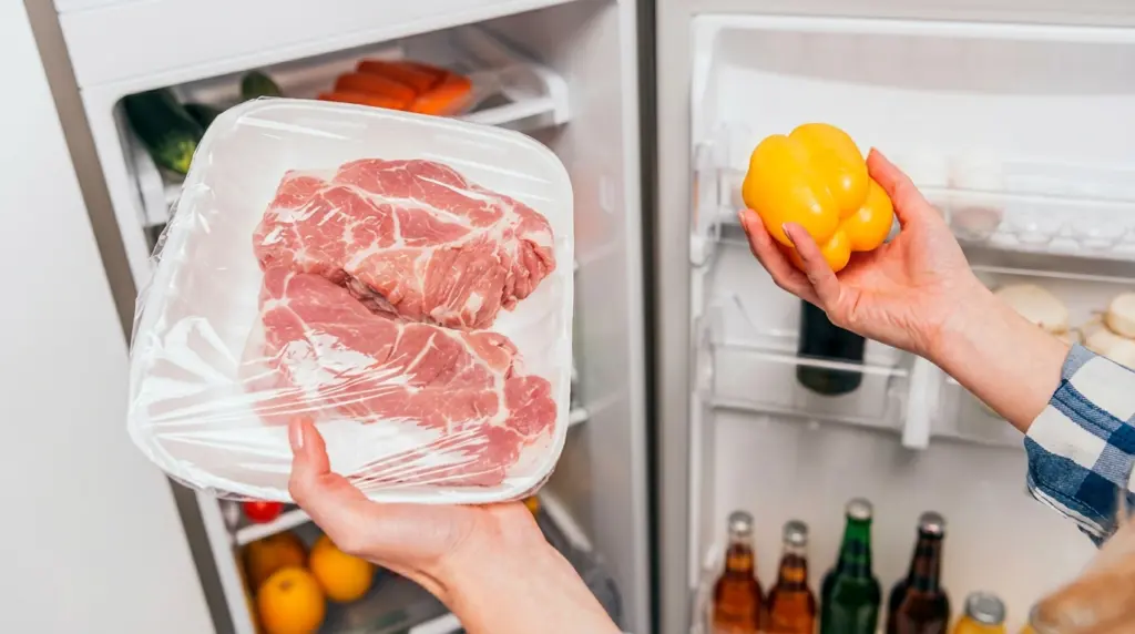 Pessoa conservando carnes na geladeira e utilizando uma tampa de pimentão amarelo para ampliar a durabilidade.