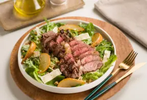 Salada com carne vermelha cozida e cortada em fatias, acompanhada de folhas verdes, fatias de laranja e queijo