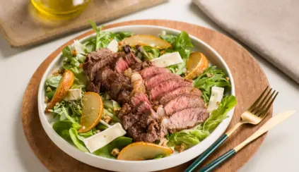 Salada com carne vermelha cozida e cortada em fatias, acompanhada de folhas verdes, fatias de laranja e queijo