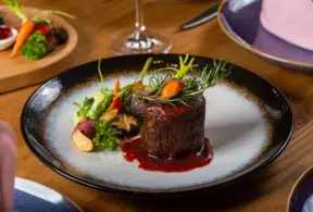 Deliciosa carne premium apresentada com molho, acompanhada de legumes e vegetais frescos em um prato sofisticado