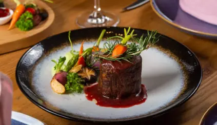 Deliciosa carne premium apresentada com molho, acompanhada de legumes e vegetais frescos em um prato sofisticado