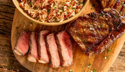 Cortes de chorizo ao ponto para malpassado servidos sobre tábua de madeira com guarnição de arroz com carne seca desfiada