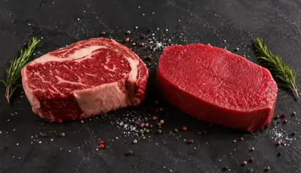 Dois cortes de carne vermelha em destaque sobre uma superfície escura: um bife com marmoreio e outro corte magro, com pimenta-do-reino e ramos de alecrim ao redor — mostrando a diferença entre carne vermelha x carne marmoreio