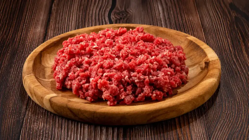 Carne moída crua em uma tigela de madeira sobre uma mesa rústica