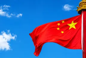 Bandeira da China com estrelas amarelas ao vento, haste vermelha com brasão dourado, em referência às novas diretrizes alimentares da China.