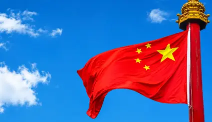 Bandeira da China com estrelas amarelas ao vento, haste vermelha com brasão dourado, em referência às novas diretrizes alimentares da China.
