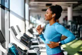Mulher correndo na esteira em uma academia, praticando exercício físico para ajudar na prevenção da sarcopenia e no fortalecimento muscular