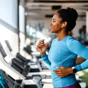 Mulher correndo na esteira em uma academia, praticando exercício físico para ajudar na prevenção da sarcopenia e no fortalecimento muscular