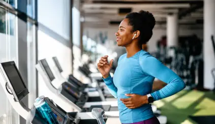 Mulher correndo na esteira em uma academia, praticando exercício físico para ajudar na prevenção da sarcopenia e no fortalecimento muscular