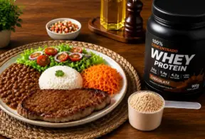 Prato com alimentos industrializados e ultraprocessados acompanhado de whey protein de chocolate e ingredientes na bancada, com temperos e porção de proteína em pó ao lado.
