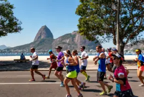 Os corredores participam de uma corrida ao longo da horla da praia. Os espectadores assistem de um banco, enquanto alguns discutem o que comer antes e depois de correr para otimizar seu desempenho e recuperação.