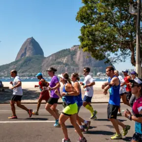 Os corredores participam de uma corrida ao longo da horla da praia. Os espectadores assistem de um banco, enquanto alguns discutem o que comer antes e depois de correr para otimizar seu desempenho e recuperação.
