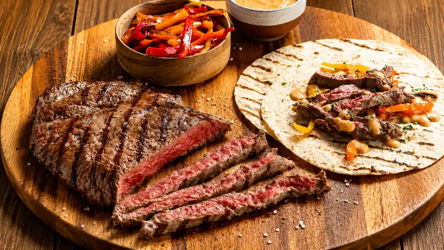 Prato com carnes grelhadas e acompanhamentos em mesa rústica, imagem relacionada ao consumo de ferro heme.