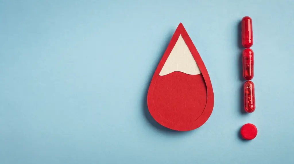 Imagem em fundo azul com símbolo de gota vermelha e cápsula de sangue ao lado, sugerindo níveis de ferro e ferritina no contexto de saúde e exames laboratoriais.