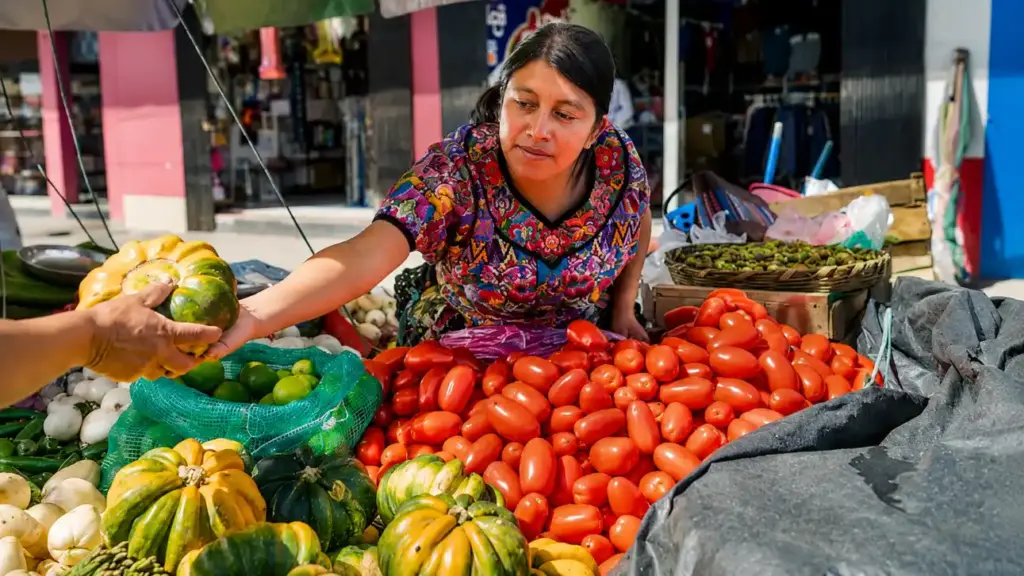 Mulher em feira de alimentos escolhendo frutas e hortaliças frescas entre abóboras, bananas e tomates, destacando segurança alimentar