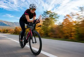 recuperación postentrenamiento: Ciclista en una carretera abierta, pedaleando a gran velocidad durante un entrenamiento al aire libre